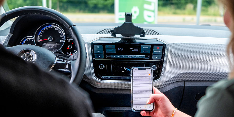 Ein Paar parkt vor einer Ökostrom-Ladesäule und sieht auf ein Smartphone