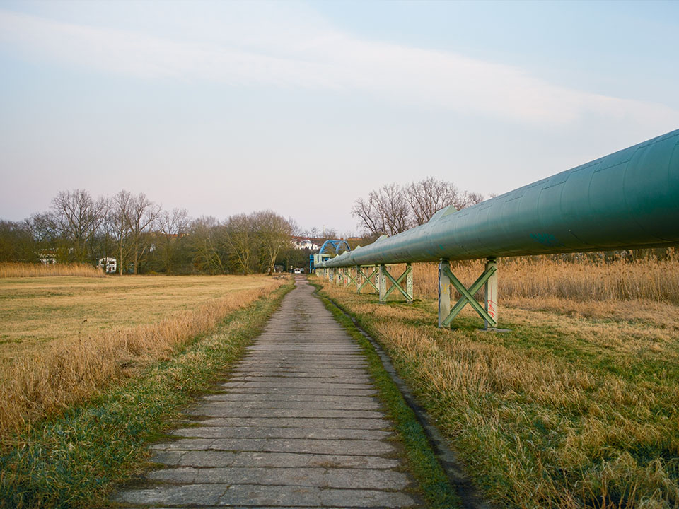 Die Rohre des Fernwärmenetzes an einem Feldweg bei Sonnenuntergang